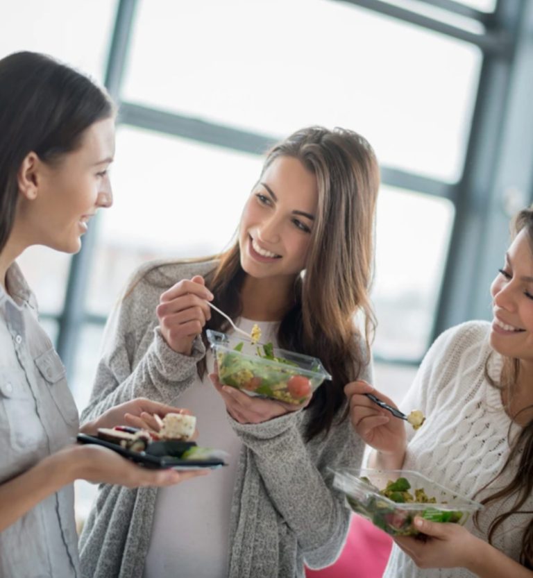 women talking and eating salads and sushi